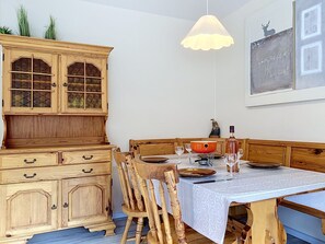 A dining area with a wooden table, chairs, and a cabinet with glass doors.