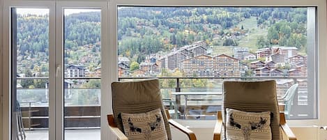 Een kamer met twee fauteuils gericht op een groot raam met uitzicht op een woonwijk.