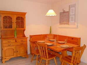 Un coin repas avec une table et des chaises en bois, un buffet avec des portes en verre et un luminaire suspendu.