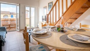 A dining area with a round table set for two, a wooden staircase, and a view of the outside. - Port Quiétude by Interhome (Fréjus)