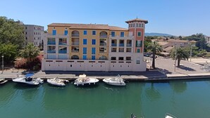 A multi-story building with balconies, a marina with several boats, and a clear sky. - Port Quiétude by Interhome (Fréjus)