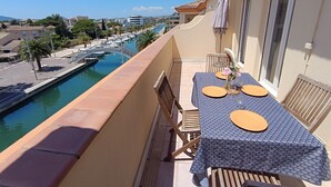 A balcony with a table set for two, overlooking a marina with boats and a clear sky. - Port Quiétude by Interhome (Fréjus)