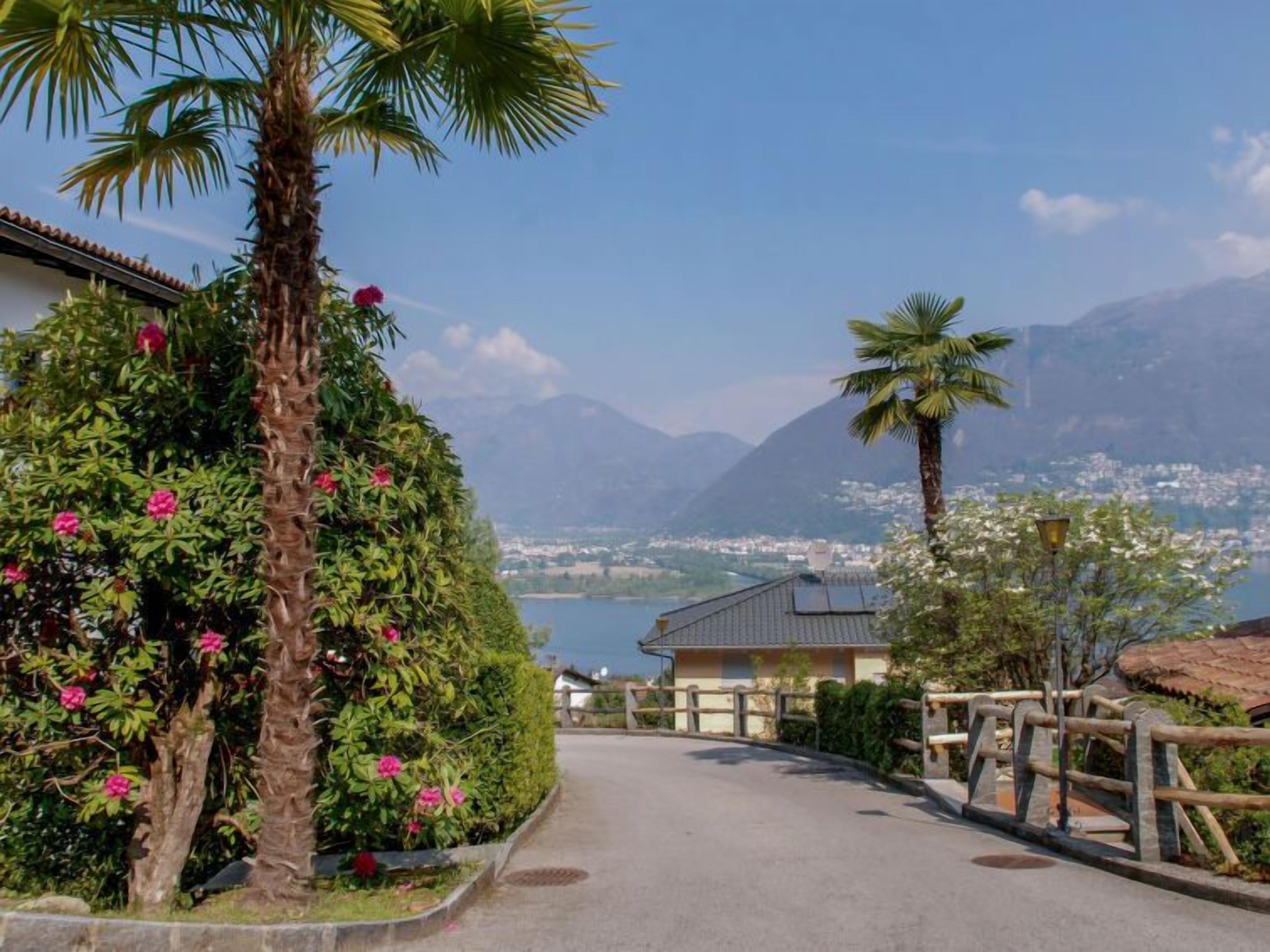A pathway leading to a building with a view of a lake and mountains.