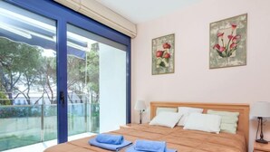A bedroom with a large bed, two wall-mounted lamps, and a view through a sliding glass door.