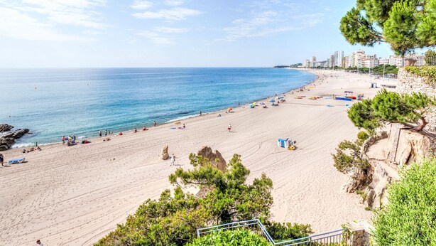 A beach with a clear view of the ocean, sandy shore, and a few people.