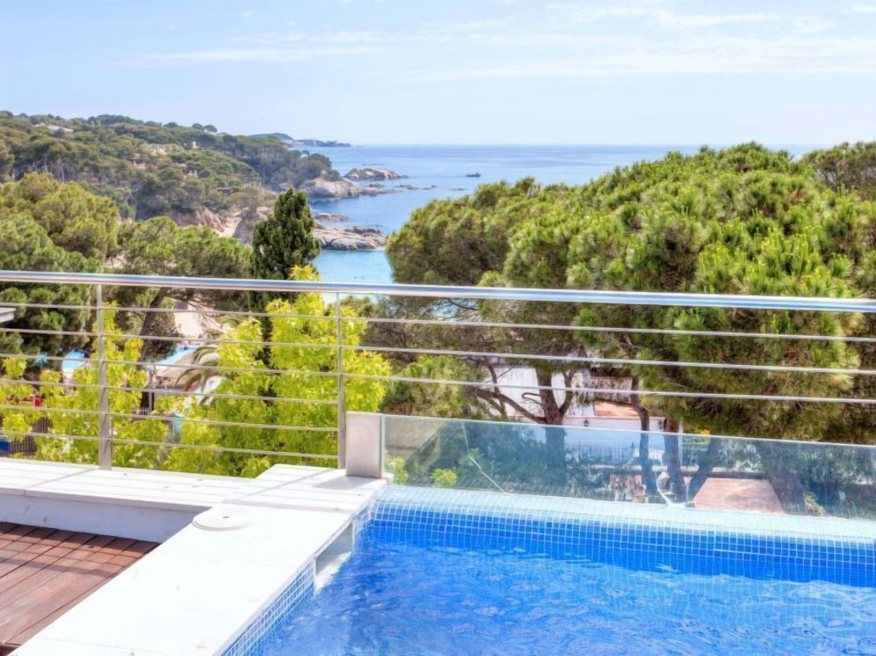 A swimming pool with a clear view of the sea and surrounding greenery.