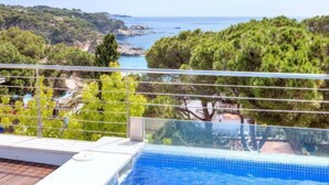 A swimming pool with a clear view of the sea and surrounding greenery.