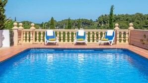 Una piscina con tres tumbonas y una barandilla.