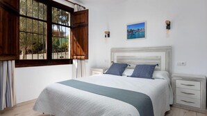 Un dormitorio con una cama grande, contraventanas de madera, una mesita de noche y un cuadro en la pared.