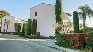 A residential area with white buildings, neatly trimmed hedges, and a palm tree. - Le Bali by Interhome (La Ciotat)