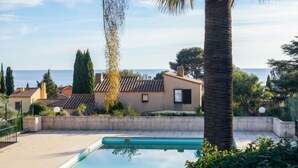 A swimming pool with a view of the sea, surrounded by palm trees and houses. - Le Bali by Interhome (La Ciotat)