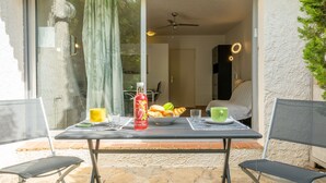 A patio with a table set for breakfast, including a bottle of tea, bread, and a cup. - Le Bali by Interhome (La Ciotat)