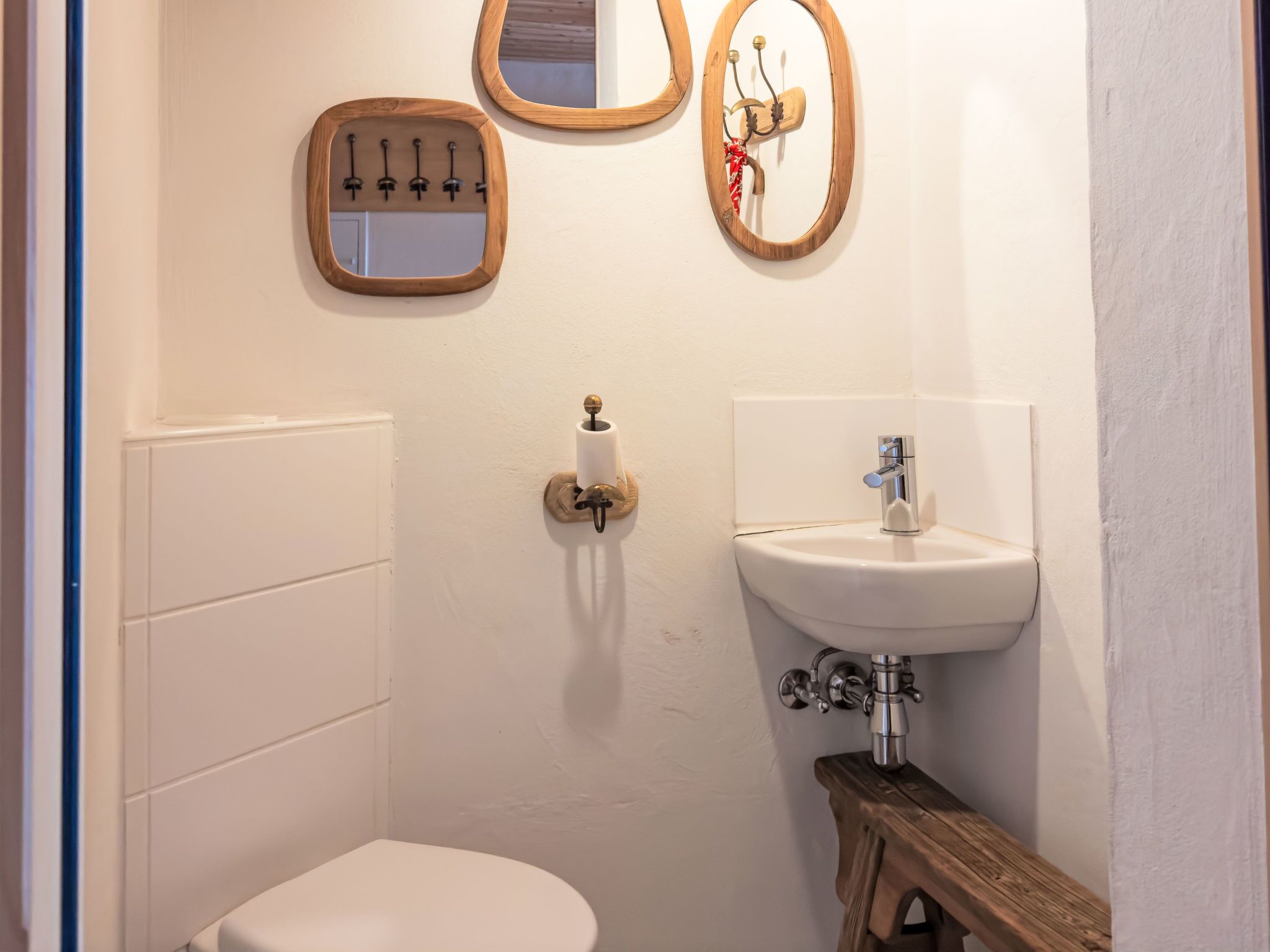 Une salle de bain équipée de toilettes, d’un lavabo et de deux miroirs fixés au mur.