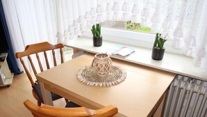A dining area with a table, chairs, a woven placemat, a candle holder, and two potted plants. - Rosengrund by Interhome (Büsum)