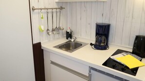 A compact kitchen with a sink, a coffee maker, and utensils hanging on the wall. - Rosengrund by Interhome (Büsum)