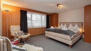 Ein Hotelzimmer mit Bett, Stuhl, Schreibtisch und einem fenster mit Vorhängen.