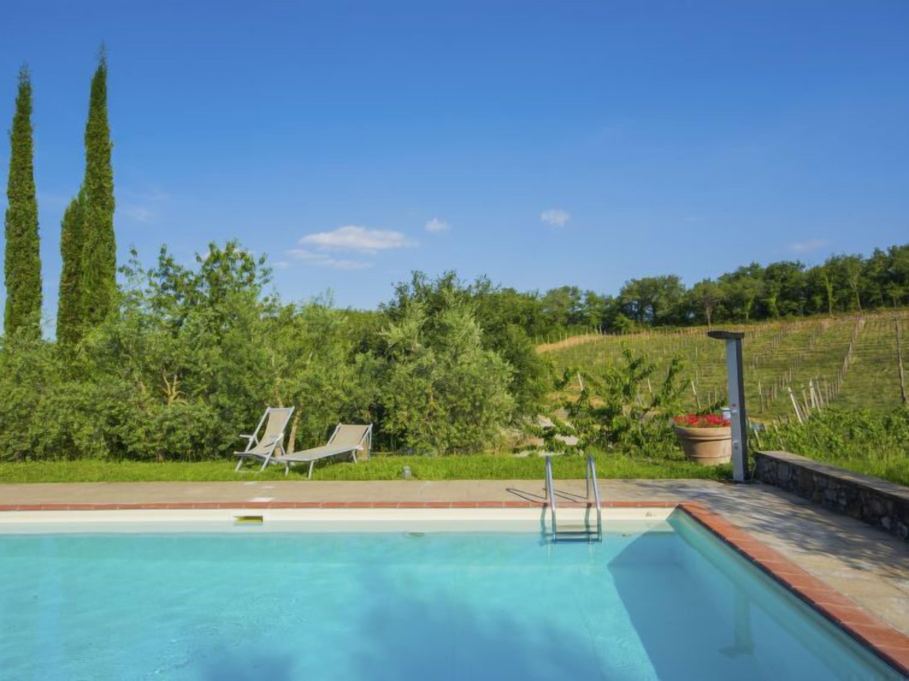 A swimming pool with lounge chairs and a pergola.
