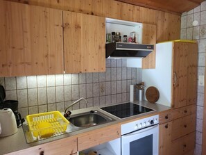 Een koelkast, een oven, kookgerei, borden en bestek