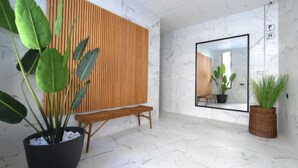 Een modern interieur met een wand van houten latten, een grote spiegel en potplanten.