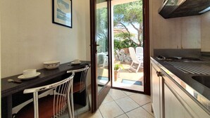 A compact kitchen with a dining area, a sliding glass door leading to an outdoor patio, and a stainless steel range hood. - La Rosa sul Mare by Interhome (Siracusa)