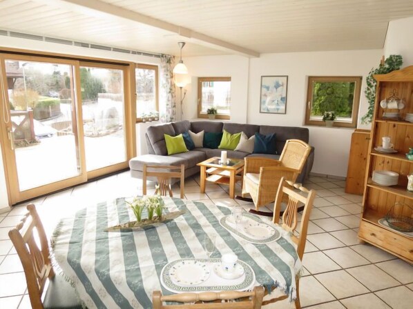 A cozy living room with a sofa, chairs, a dining table set for two, and a bookshelf. - Fischer by Interhome (Lechbruck am See)