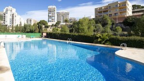 A swimming pool with clear blue water, surrounded by greenery and buildings in the background. - Apartment Zeus by Interhome (Calpe/Calp)