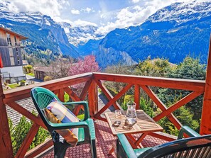 A balcony with a table and chairs overlooking a mountainous landscape.