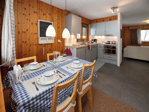 Una cocina acogedora con paredes de madera, una mesa de comedor lista con platos y cubiertos, y un horno moderno.