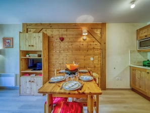 Une table de salle à manger en bois, mise avec des assiettes, des verres et un saladier.