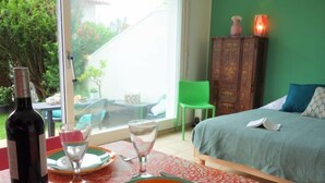 Una habitación con una cama, una mesa con una botella de vino, copas y platos.