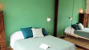 Una habitación con dos camas, paredes verdes y un armario de madera.