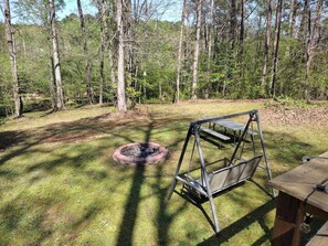 En trädgård med en eldstad, en gunga och ett picknickbord.