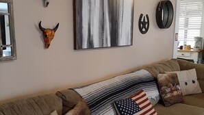 A cozy living room with a sofa adorned with various decorative pillows, including an American flag pillow. - The South River Cottage (Stockbridge)