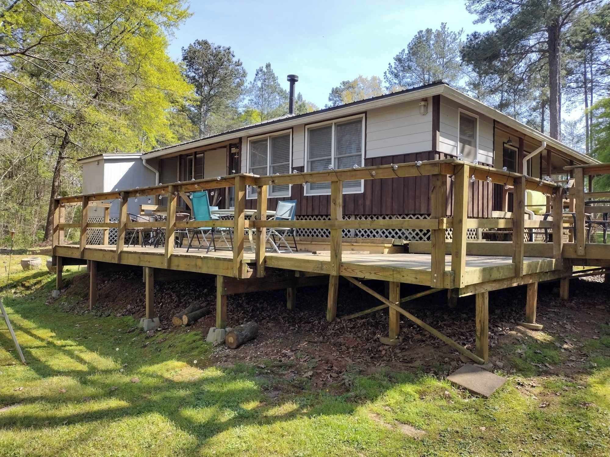 A wooden deck with outdoor furniture, a covered area, and a building with windows.