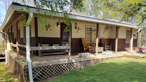 A covered outdoor area with a wooden bench, a table, and a lawn. - The South River Cottage (Stockbridge)