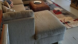 A living room with a sectional sofa, two ottomans, a ceiling fan, and a television. - The South River Cottage (Stockbridge)
