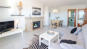 A modern living room with a flat-screen TV, a fireplace, a dining area with a table and chairs, and a sofa. - Nautic 3 by Interhome (Port d'Alcúdia)