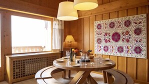 Un'area pranzo in legno con un tavolo rotondo, panche e lampade a sospensione.