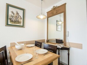 Ein Essbereich mit Holztisch, Stühlen, einem großen Spiegel und einem gerahmten Gemälde an der Wand.