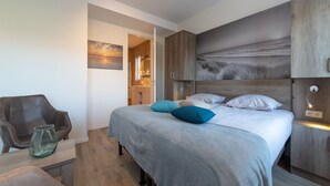 Un dormitorio moderno con cama, una silla y una mesita de noche.