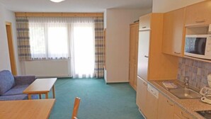 Ein kompakter Wohnbereich mit Küchenzeile, einem Essbereich mit Tisch und Stühlen sowie einer Couch.