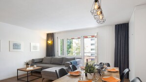 A modern living room with a dining area, a sofa, a coffee table, and a dining table set for four. - Allod Park Haus C 105 by Interhome (Davos)