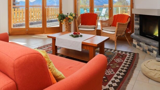 Ein gemütliches Wohnzimmer mit Kamin, einer Couch und einem Tisch mit Blumenvase.