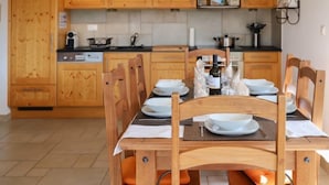 Ein Essbereich mit Holzkreisen und einem Tisch für vier Personen, eine Mikrowelle über der Arbeitsplatte und Holzschränke im Hintergrund.