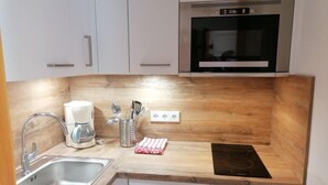 Una cocina moderna con encimera de madera, pileta de acero inoxidable y horno empotrado.