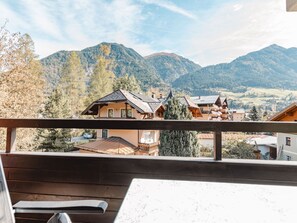 A mountain village with traditional wooden houses, a wooden deck, and a view of the surrounding hills.