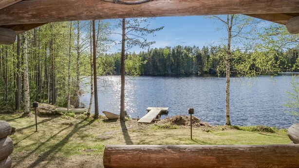 A wooden cabin with a view of a lake surrounded by trees.
