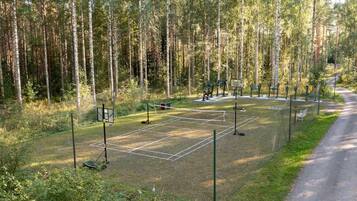 A basketball court surrounded by a forest with tall trees.