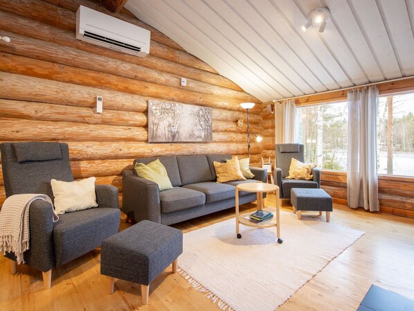 Ein Blockhaus-Interieur mit einer Couch, einem Hocker und einem Tisch.