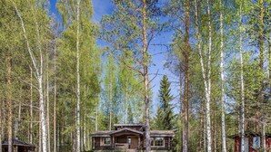A cabin surrounded by tall trees and a lake.
